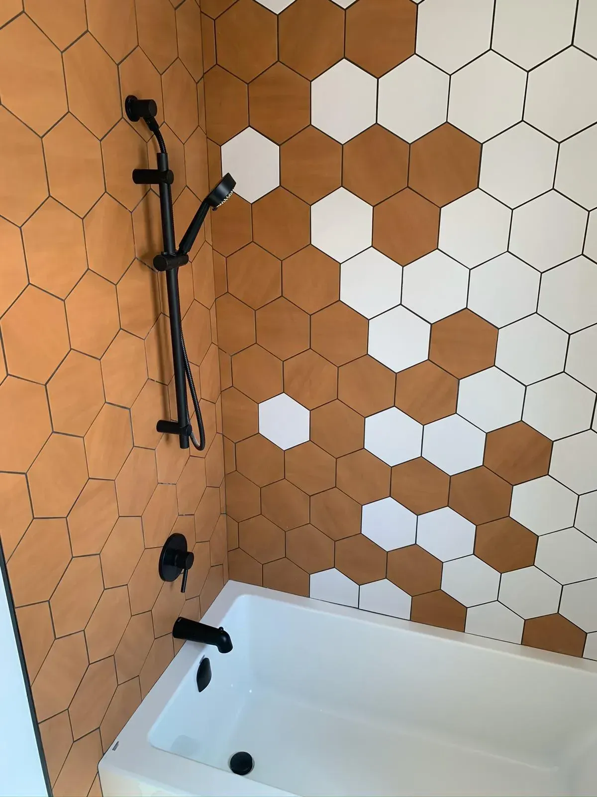 A bathroom with hexagon tiles on the wall and a bathtub