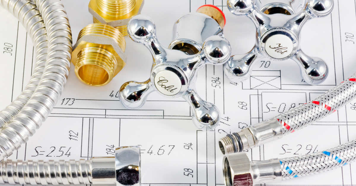 Plumbing tools like faucets and hoses on top of a blueprint.