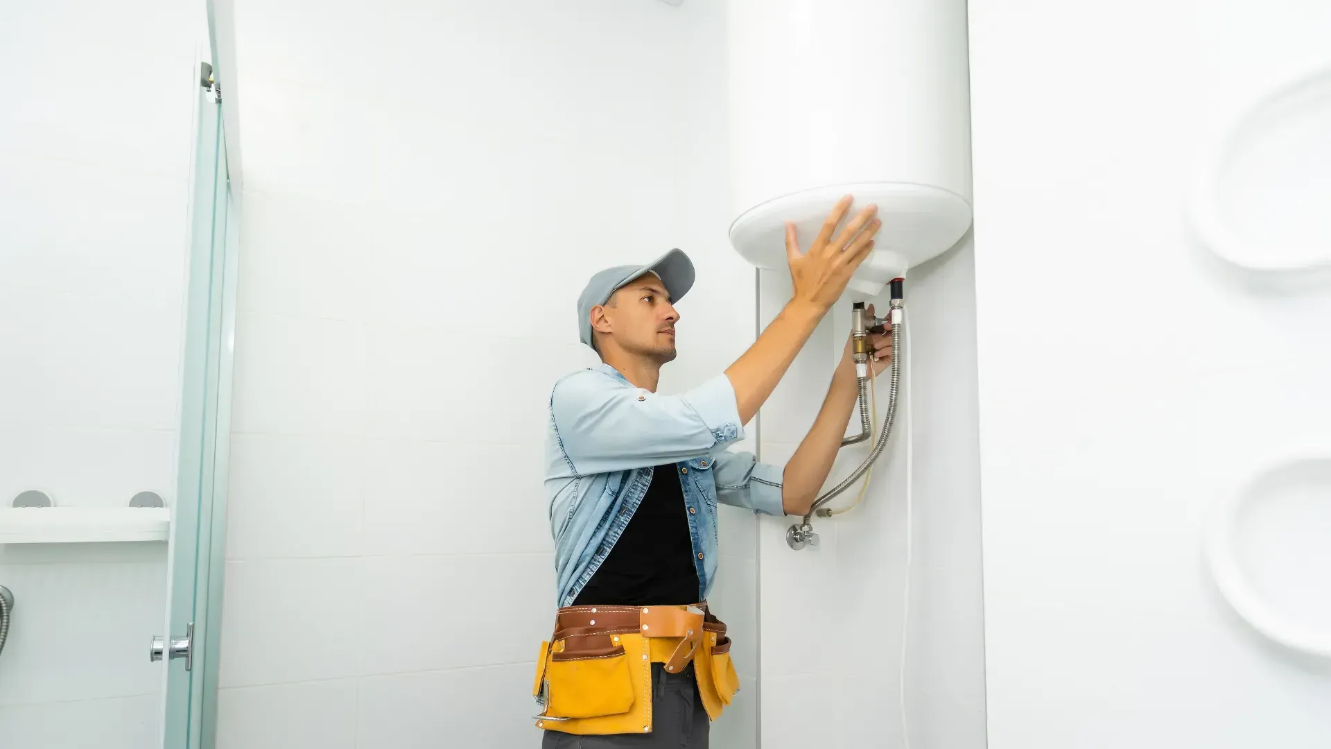 A man is fixing a water heater in a bathroom.