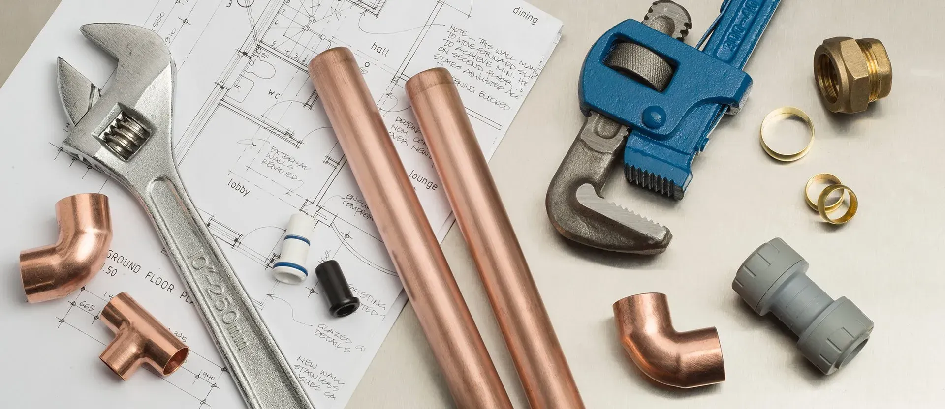 Copper pipes , wrenches , fittings and a drawing on a table