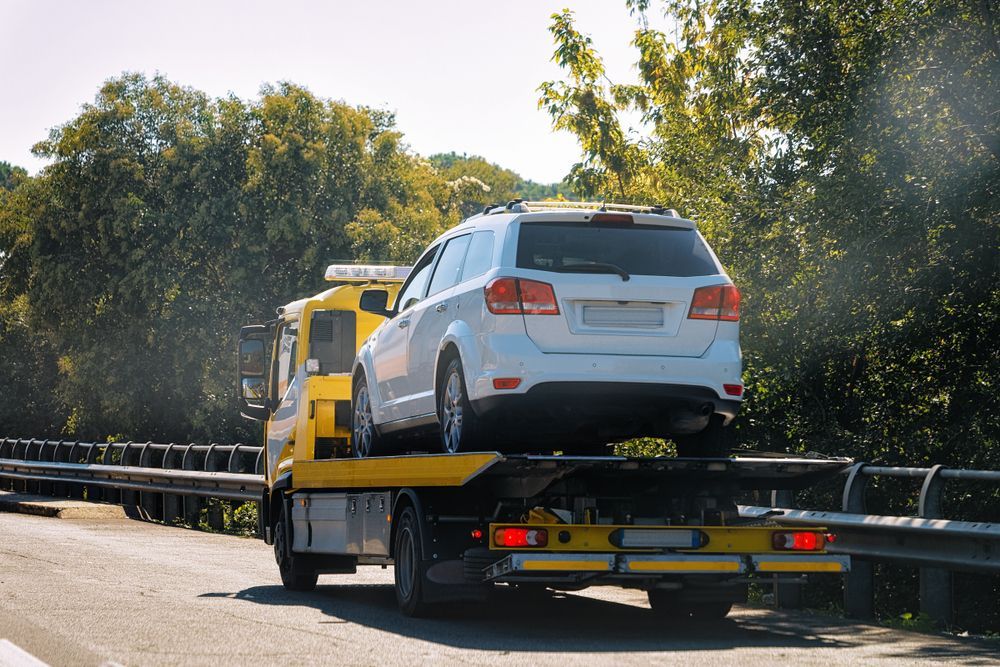 A White SUV is Being Towed by a Tow Truck on a Highway — Tamworth Manual Transmission Factory In Taminda, NSW