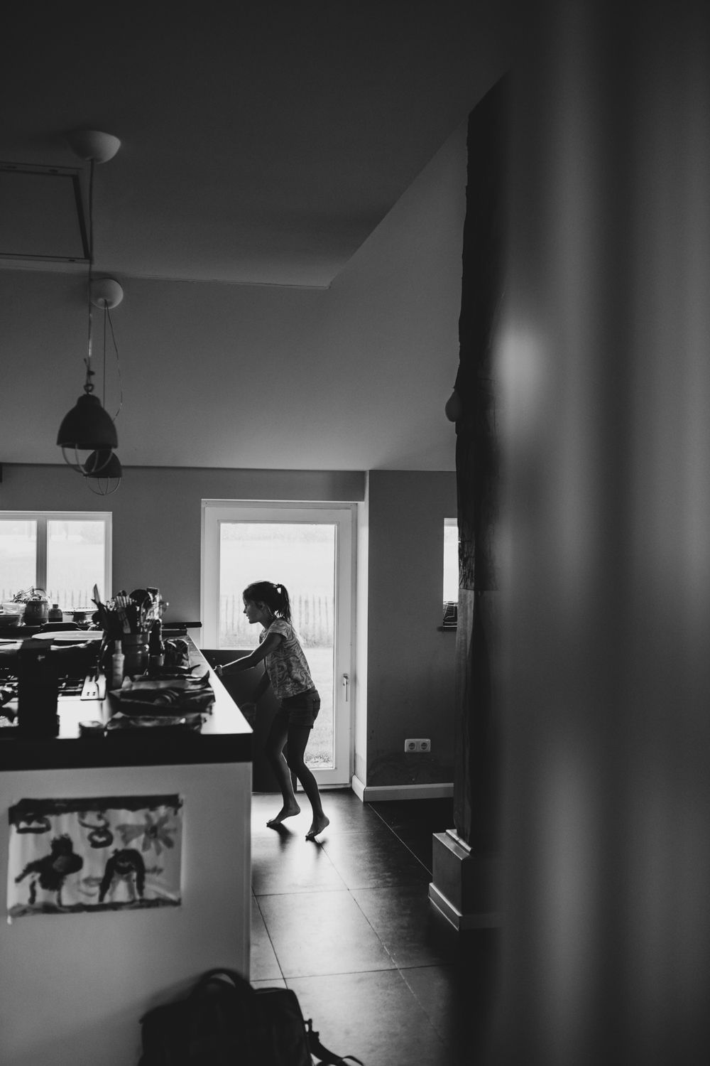 Een silhouet van een persoon die aan een toonbank staat in een schemerig verlichte, moderne keuken.