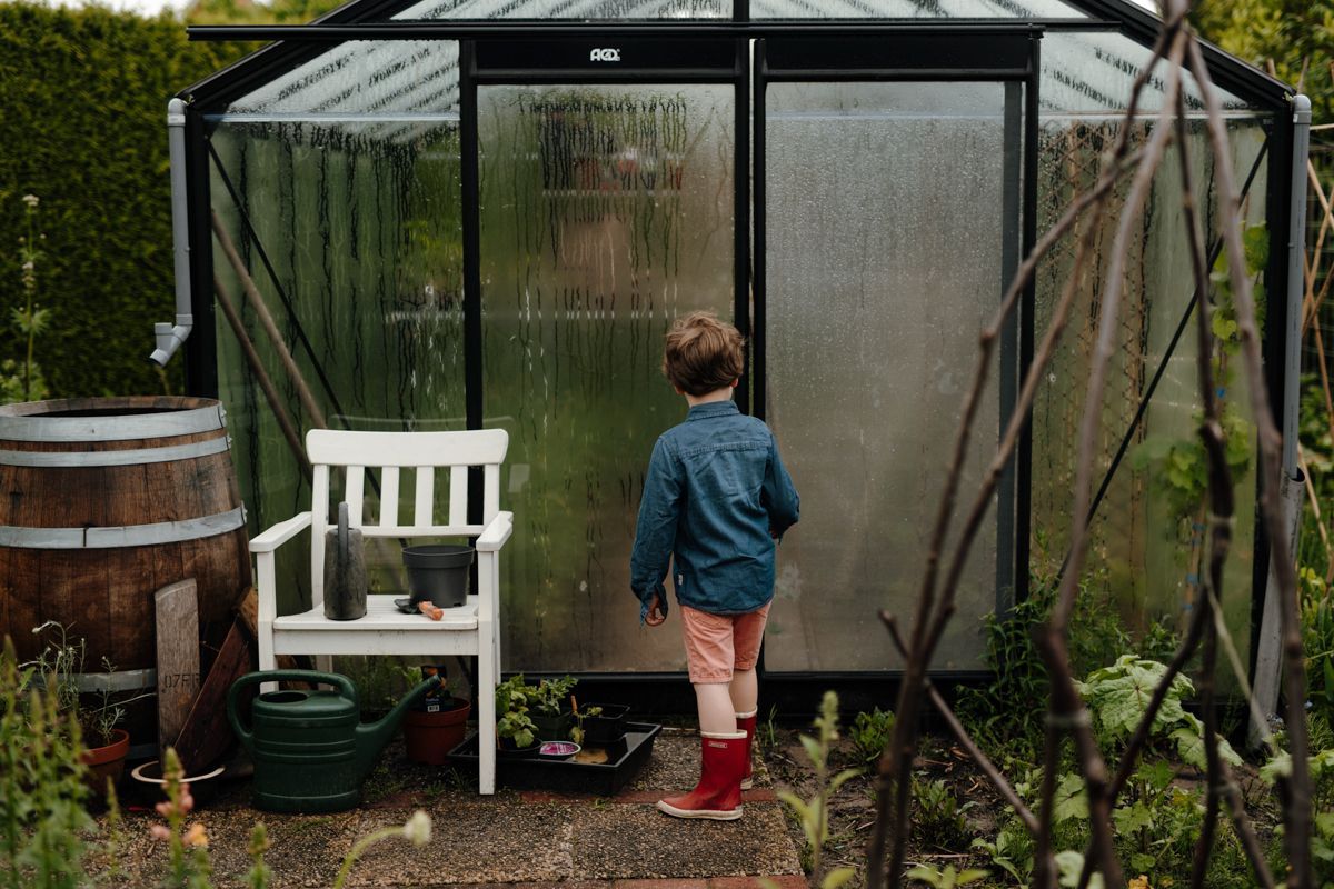 Jongetje voor de kas tijdens de laatste warme zomerdagen
