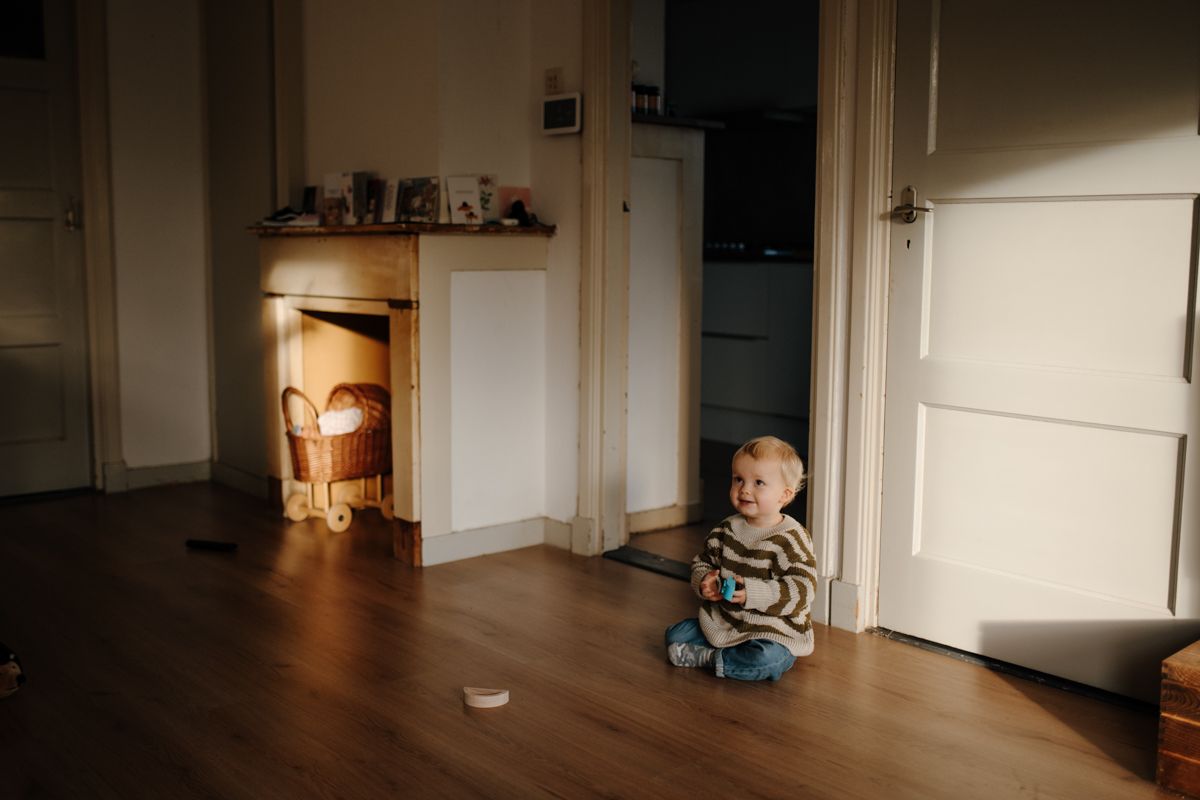 Peuter zit in de mooie woonkamer tijdens een gezinsshoot
