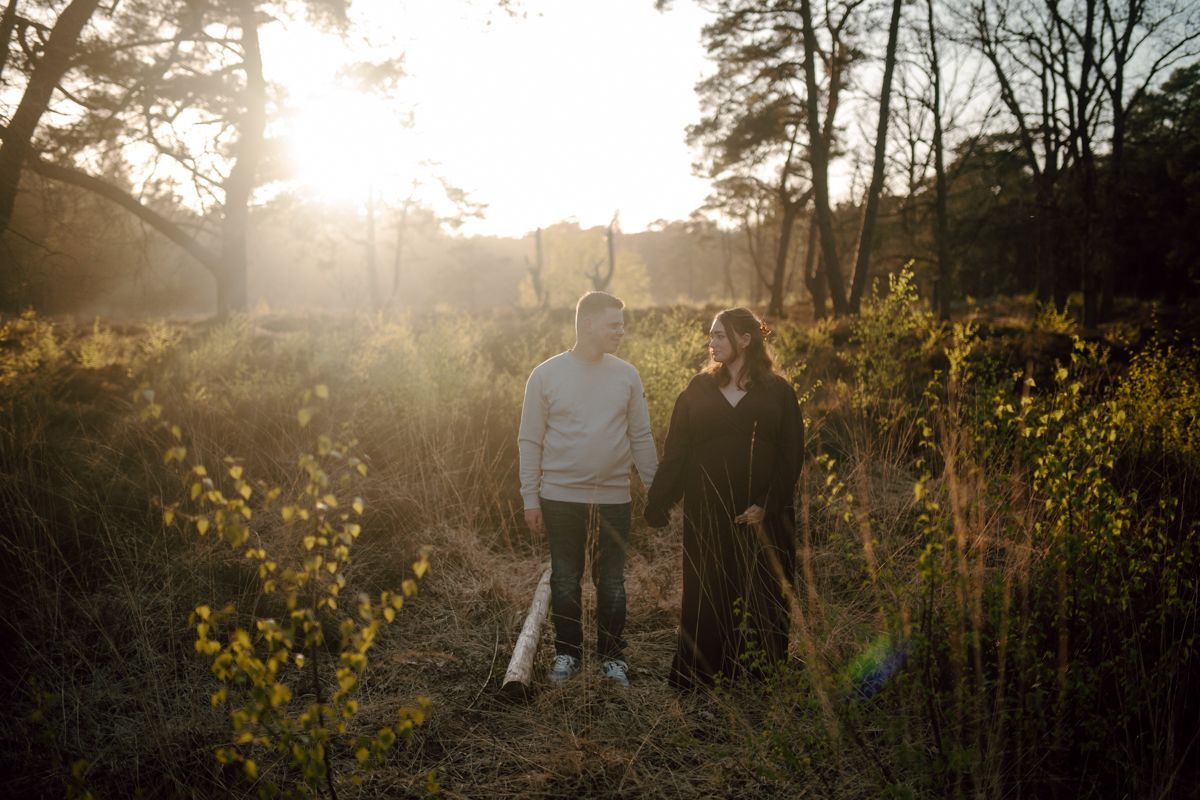 Twee mensen staan in het bos tijdens een fotoshoot met zonsondergang