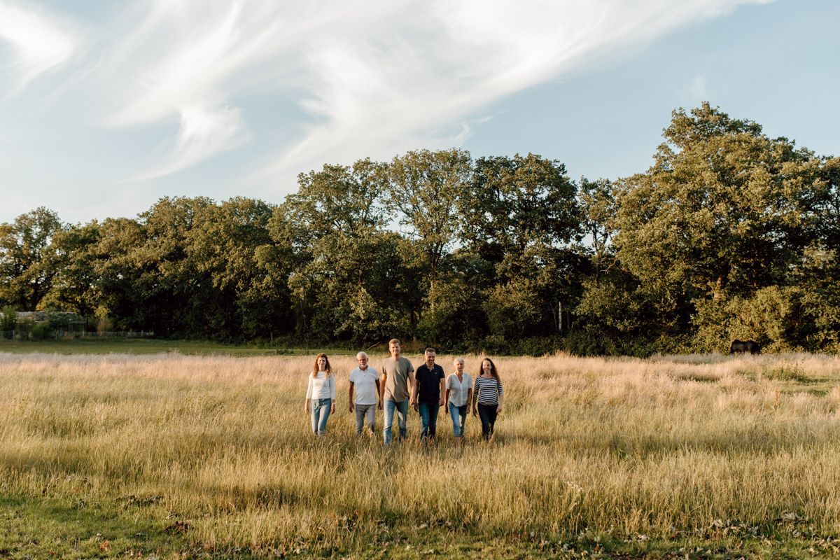 Een kleine groep staat in een grasveld met bomen en een bewolkte hemel op de achtergrond.