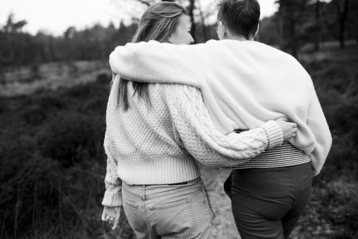Twee mensen lopen arm in arm door een grasveld, in zwart-wit.