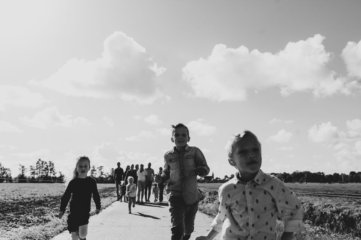 Kinderen lopen over een strand onder een bewolkte hemel, met anderen in de verte langs de kustlijn.