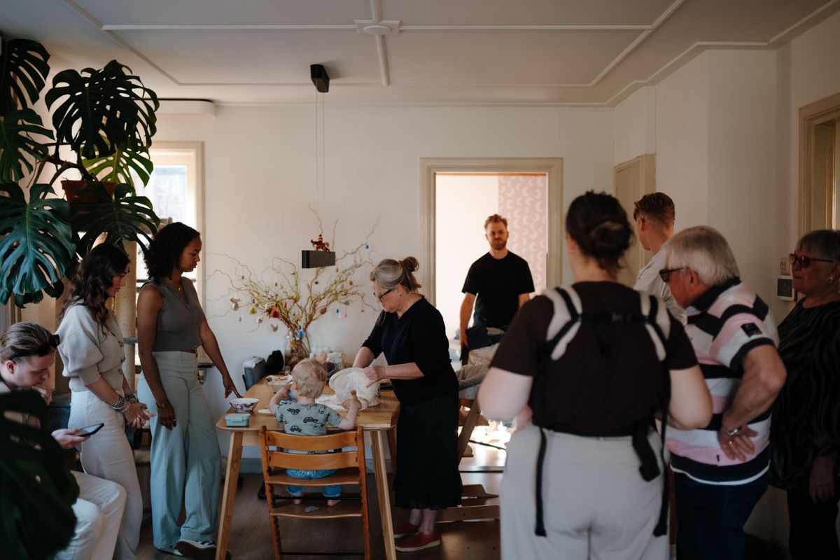 Een groep mensen komt samen in een licht huis voor een knutselactiviteit, waarbij een jong kind aan een houten eettafel zit.