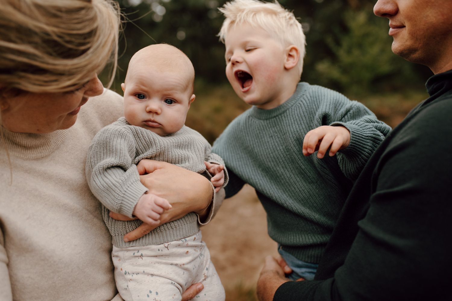 Een vrouw houdt een baby vast terwijl een man en twee kinderen toekijken.