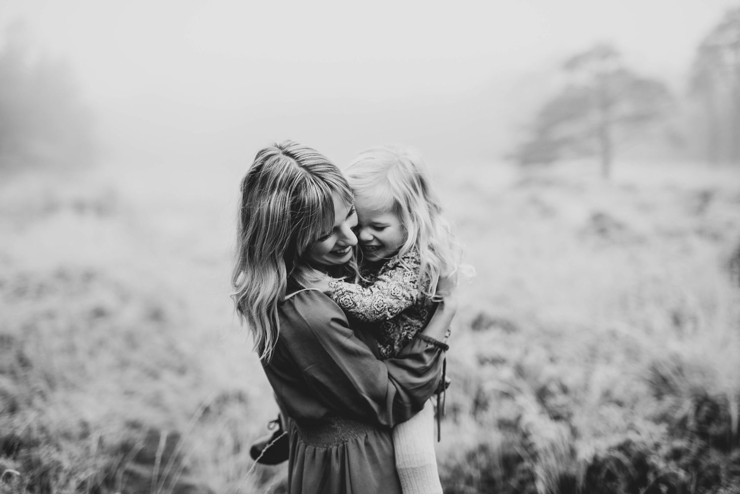 Twee kinderen die elkaar buiten omhelzen in een wazig zwart-wit beeld.