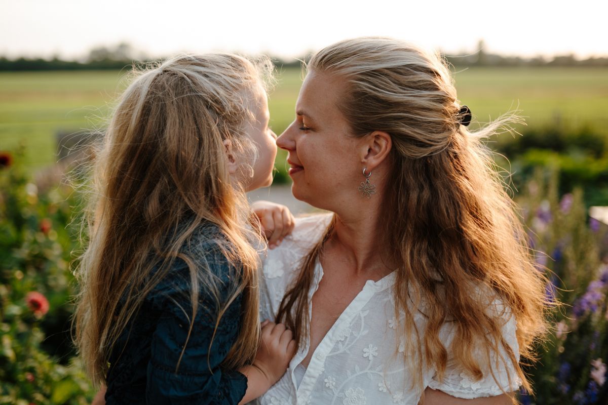 Moeder en dochter knuffelen tijdens de fotoshoot in de pluktuin