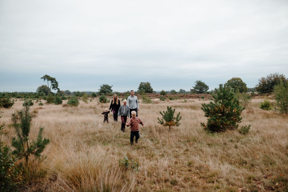 Mensen lopen door een droog grasveld onder een bewolkte hemel.