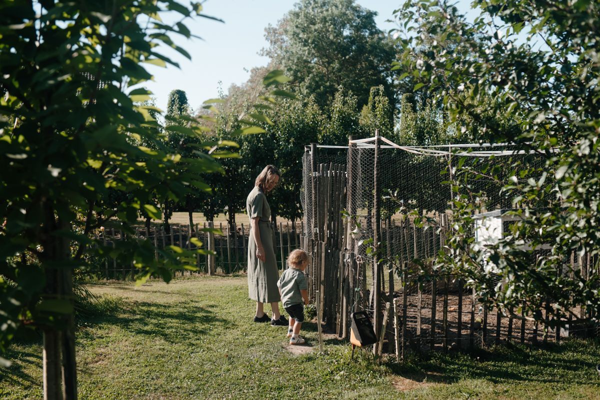 Moeder en zoontje lopen naar de kippenren in de achtertuin
