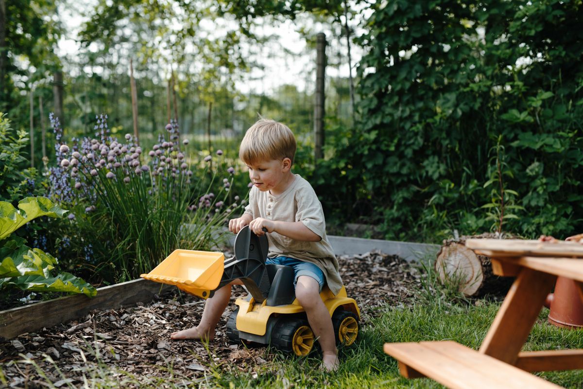 Jongetje op de traptrekker door de moestuin om te spelen tijdens tijdens een gezinsshoot