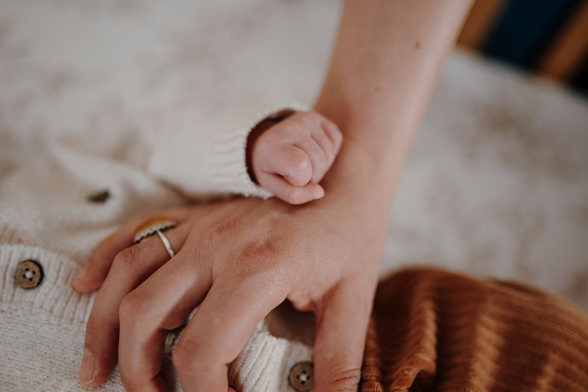 Babyhandje op de hand van moeder tijdens de newbornshoot in sneek