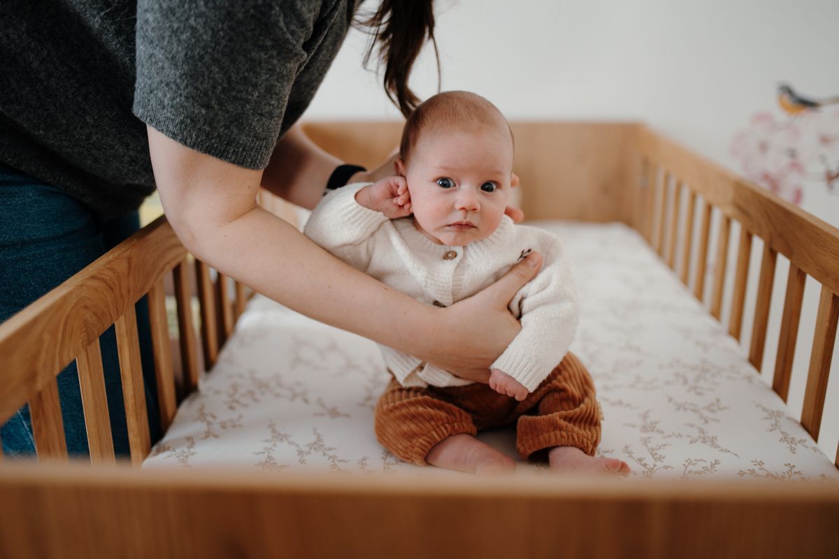 Baby zit in ledikantje op de foto tijdens de newbornshoot