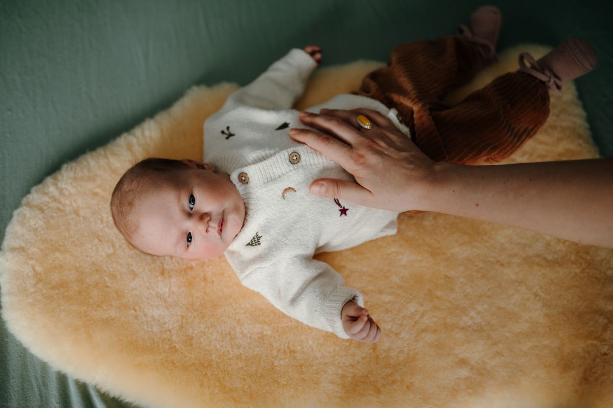 Hand van moeder op de buik van de baby tijdens de newbornshoot