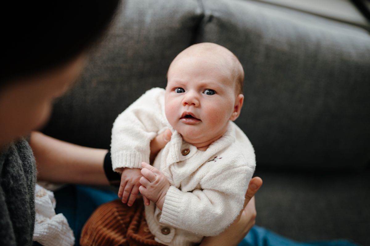 Newbornshoot in Sneek - pasgeboren dochter zit bij moeder op schoot