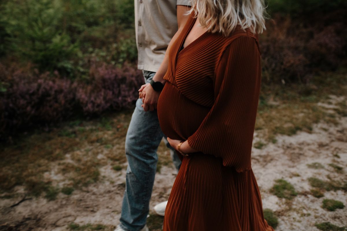 Zwangere vrouw met haar partner tijdens een zwangerschapsshoot in de heide van Drenthe