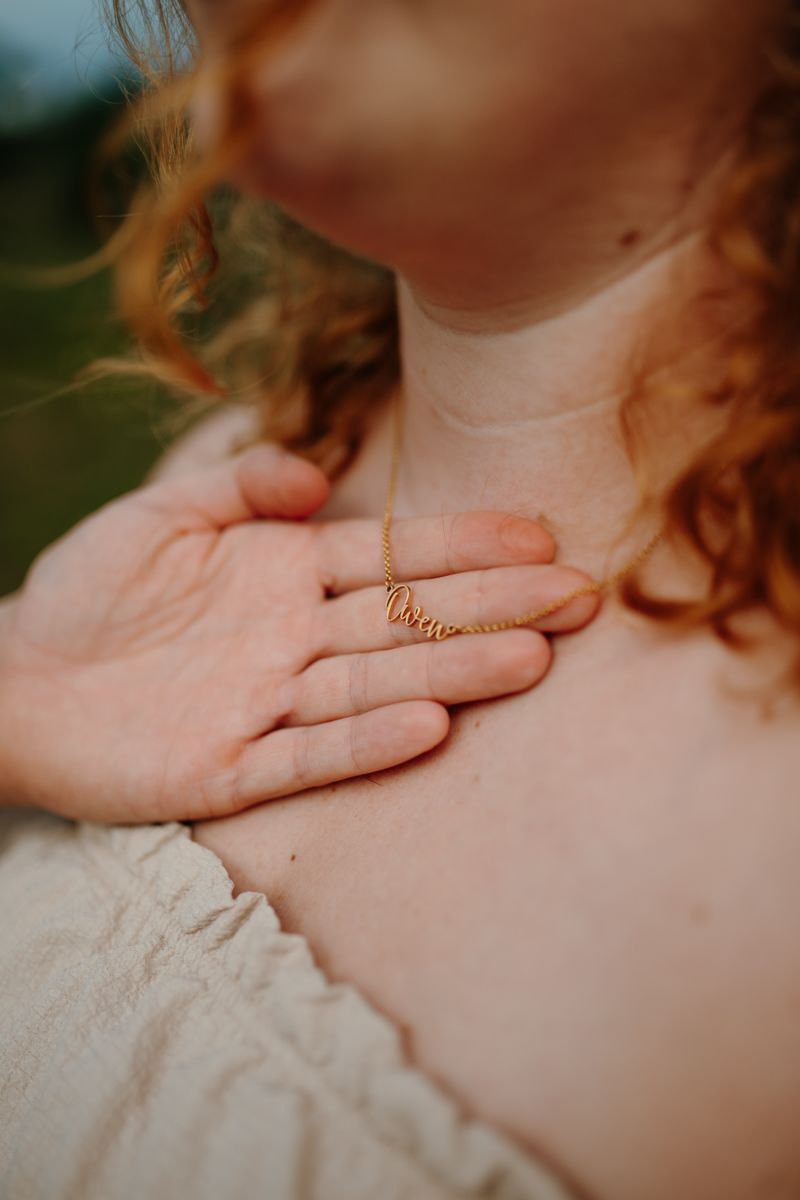 Detailfoto van naamketting Owen op de borst van een zwangere vrouw, zwangerschapsshoot Appelscha