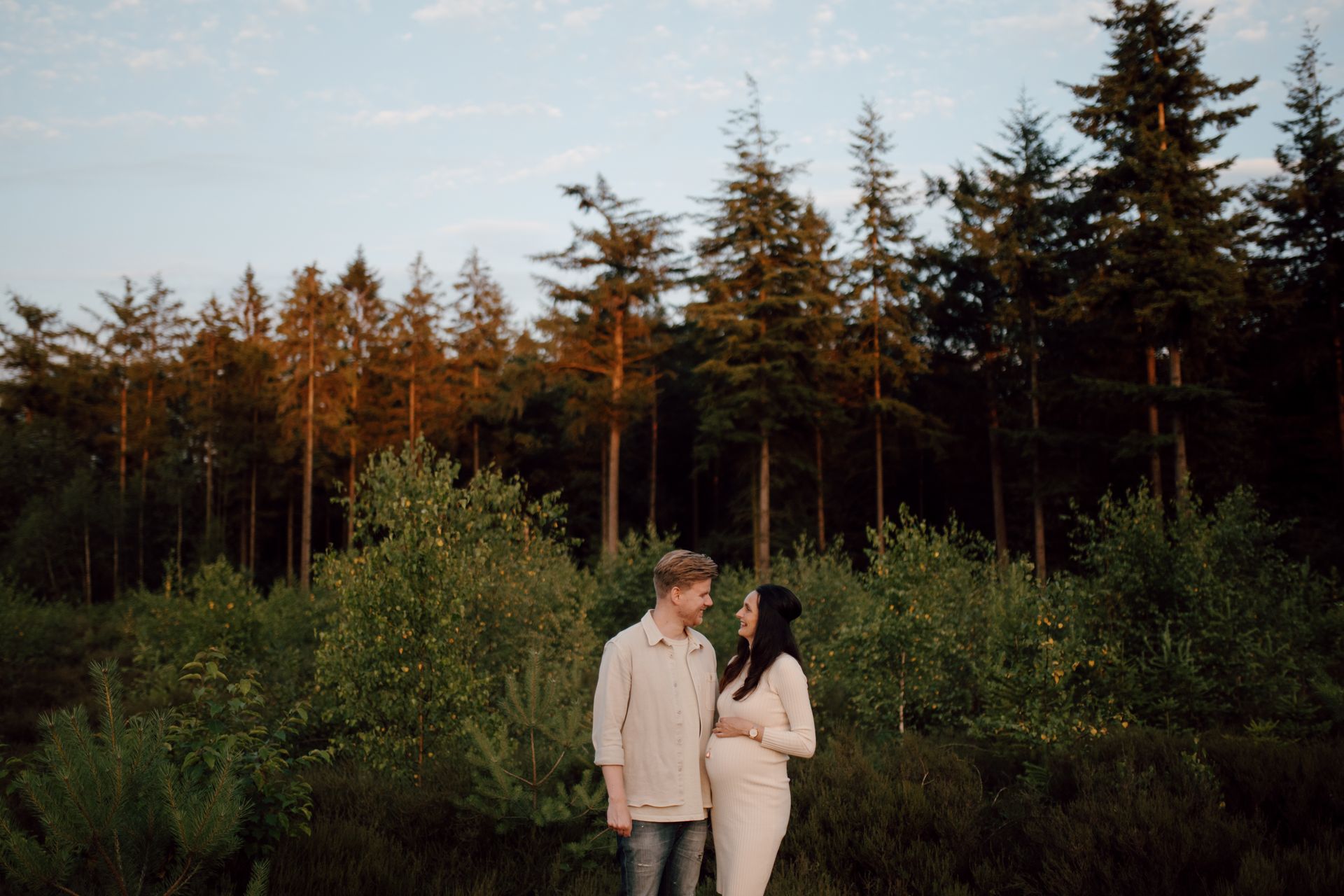 Zwanger stel samen in de het bos tijdens een fotoshoot bij zonsondergang