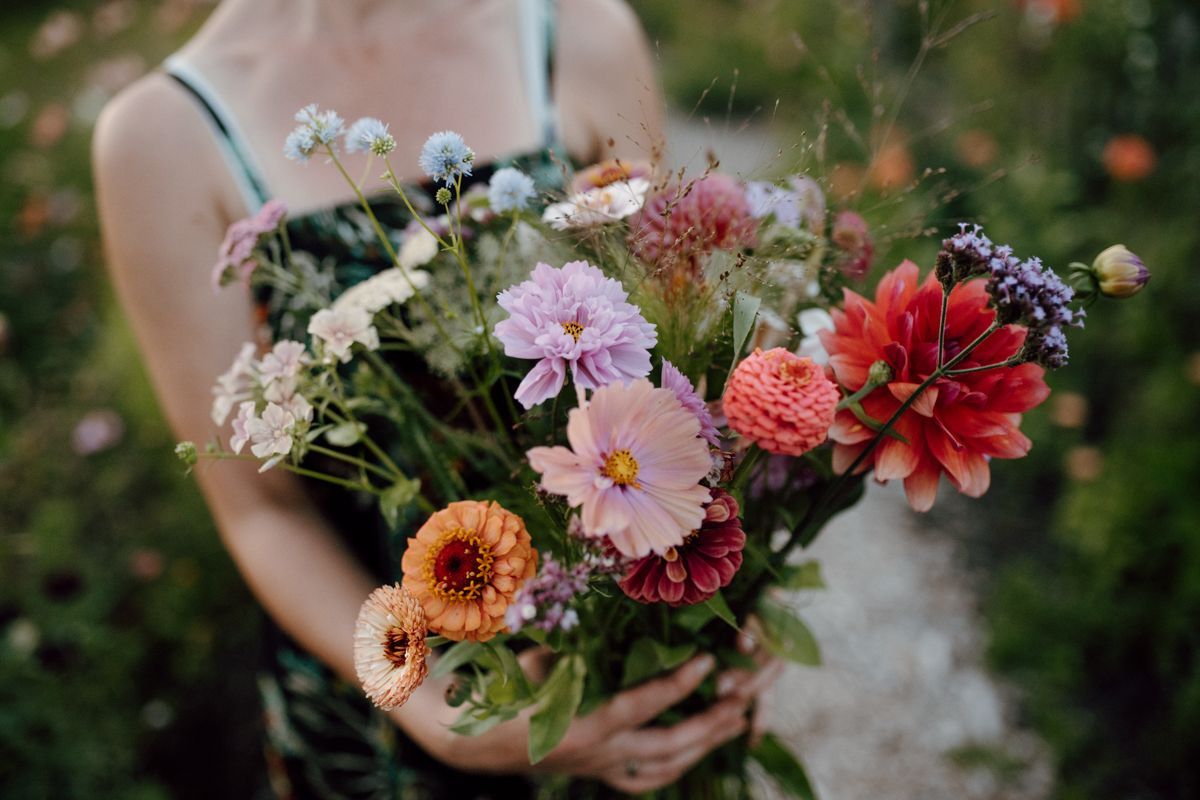 Een vrouw houdt een boeket bloemen in haar handen.