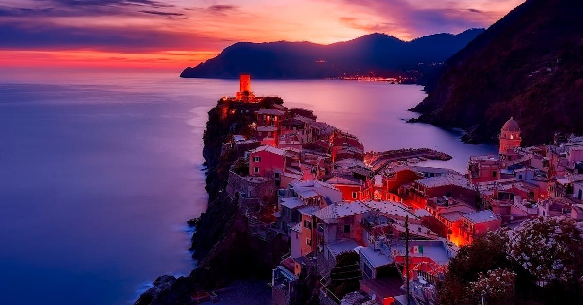 A city on a cliff overlooking the ocean at sunset.