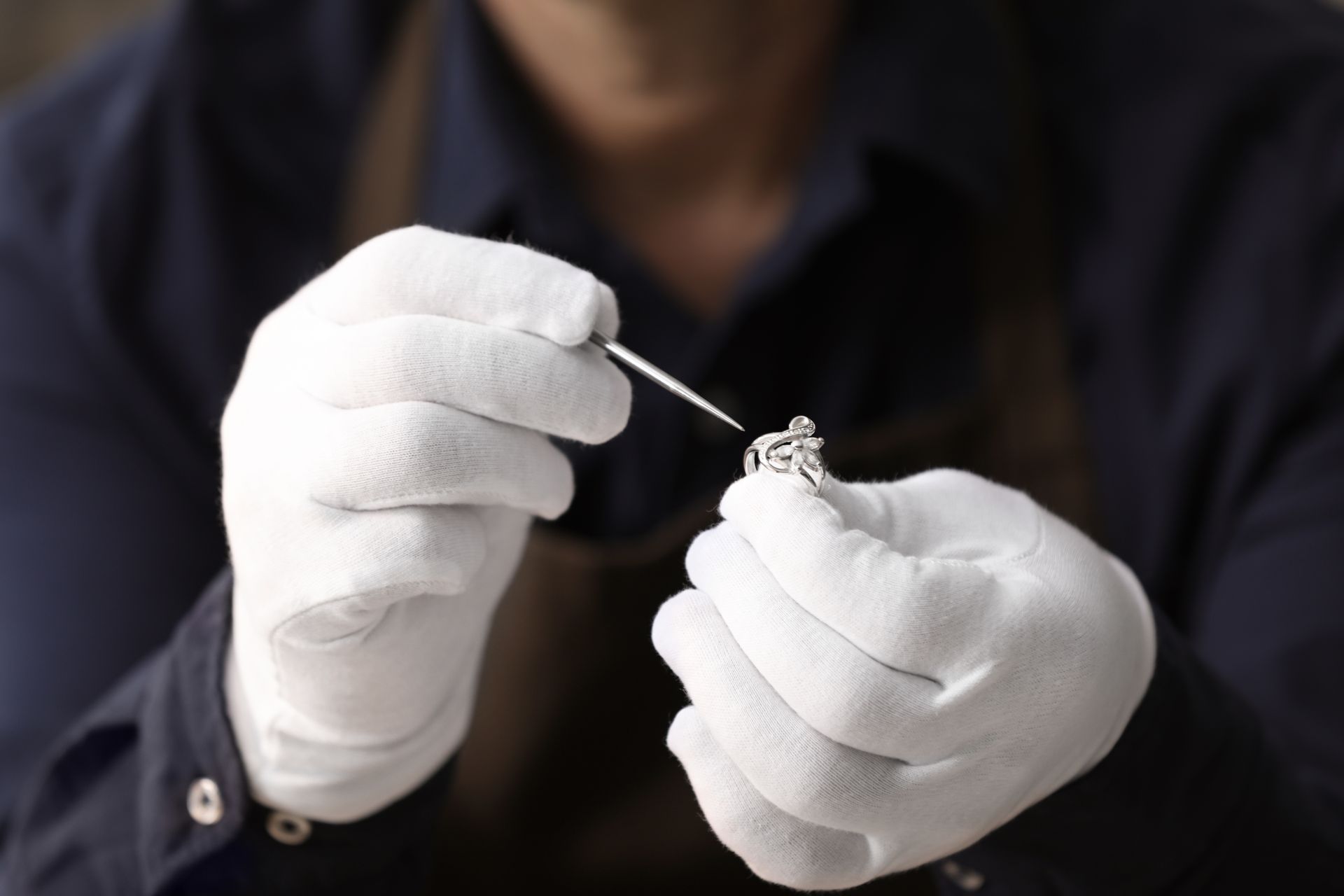 Diamond Rings — Birmingham, MI — Fredrick Jewelers White-gloved hands cleaning and restoring a jewelry piece using fine precision tools.