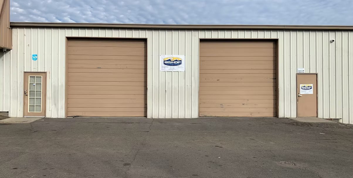 Tan building with two large garage doors and two smaller doors.