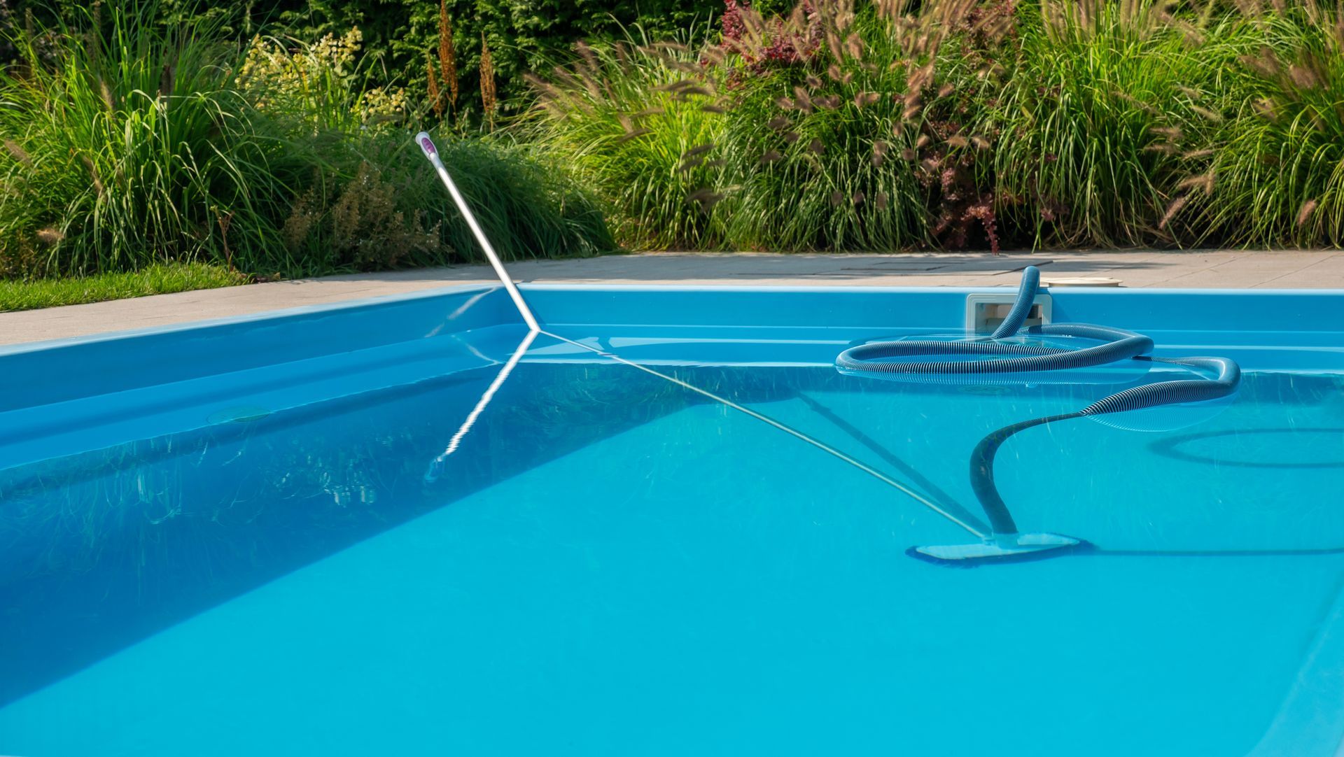 Pool cleaning equipment floating in a bright blue swimming pool near the edge.