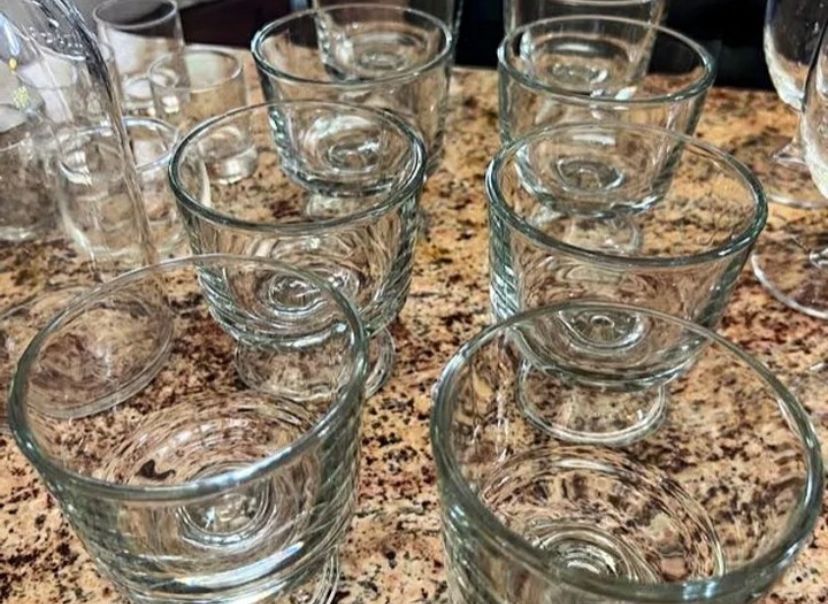 Clear glass tumblers arranged on a speckled countertop.