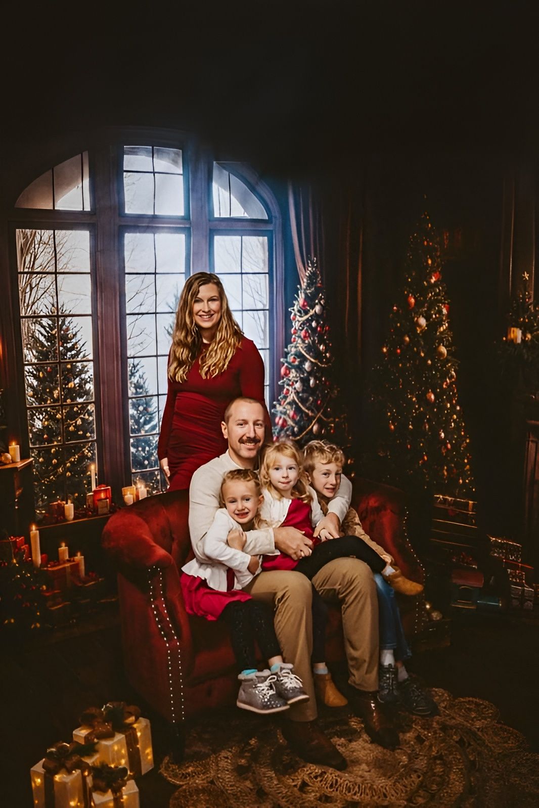 Family posing by a decorated Christmas tree in a cozy, candlelit room