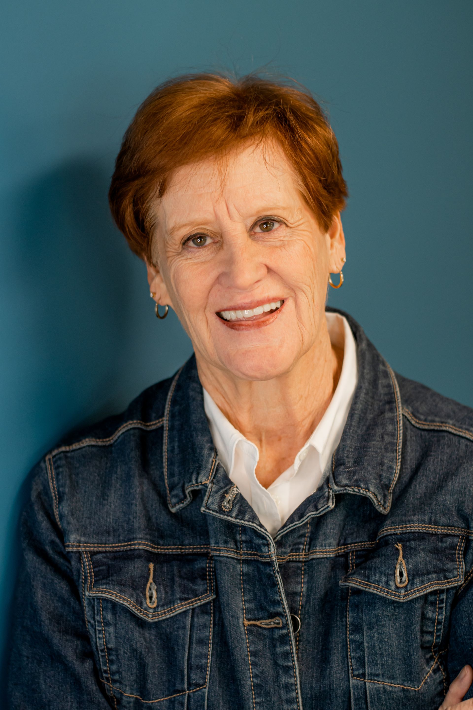 Smiling woman in a denim jacket against a blue background