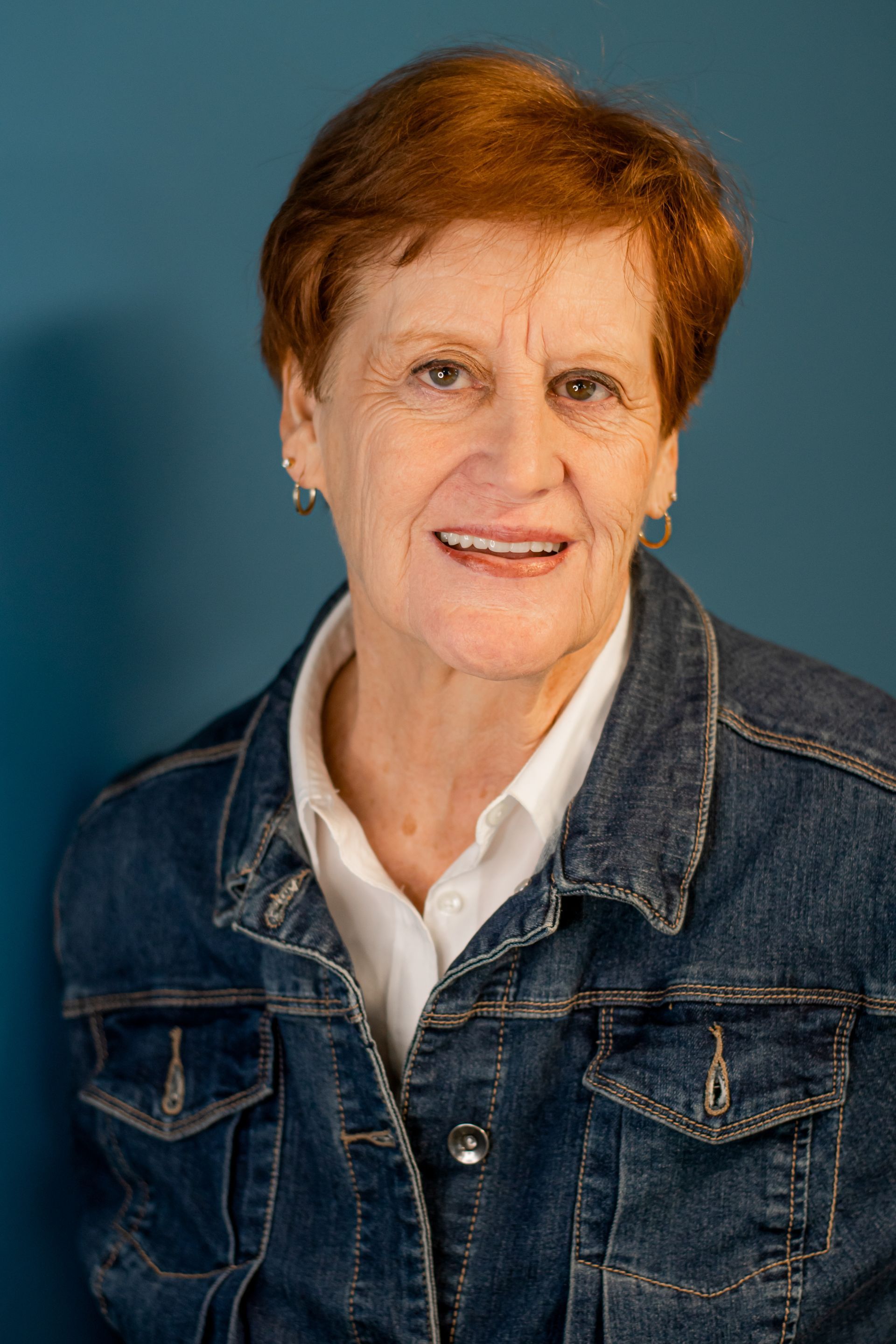 Smiling person in a denim jacket against a blue background