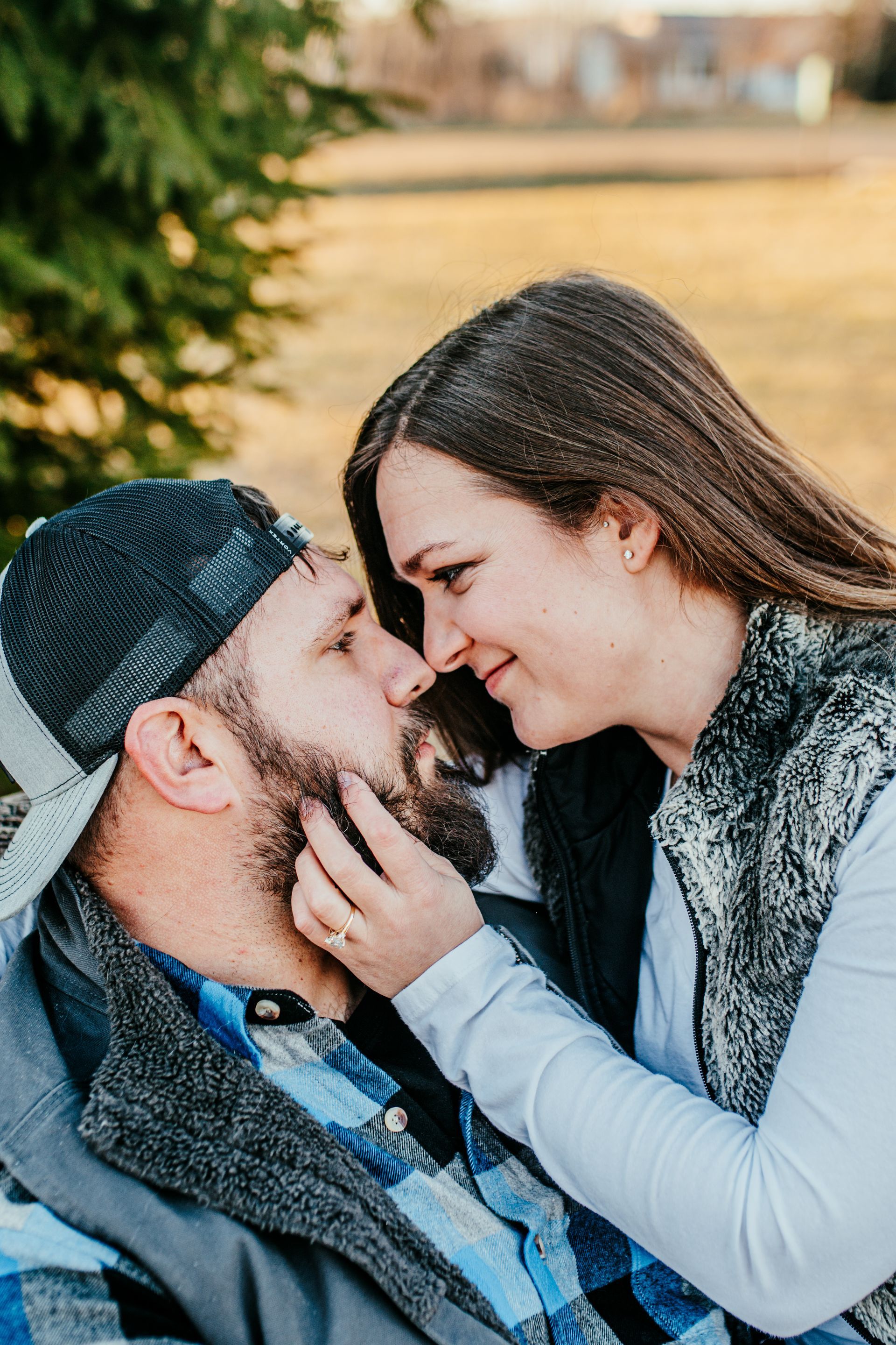 Couple sharing a tender nose-to-nose moment outdoors, with the woman gently touching the man's face.