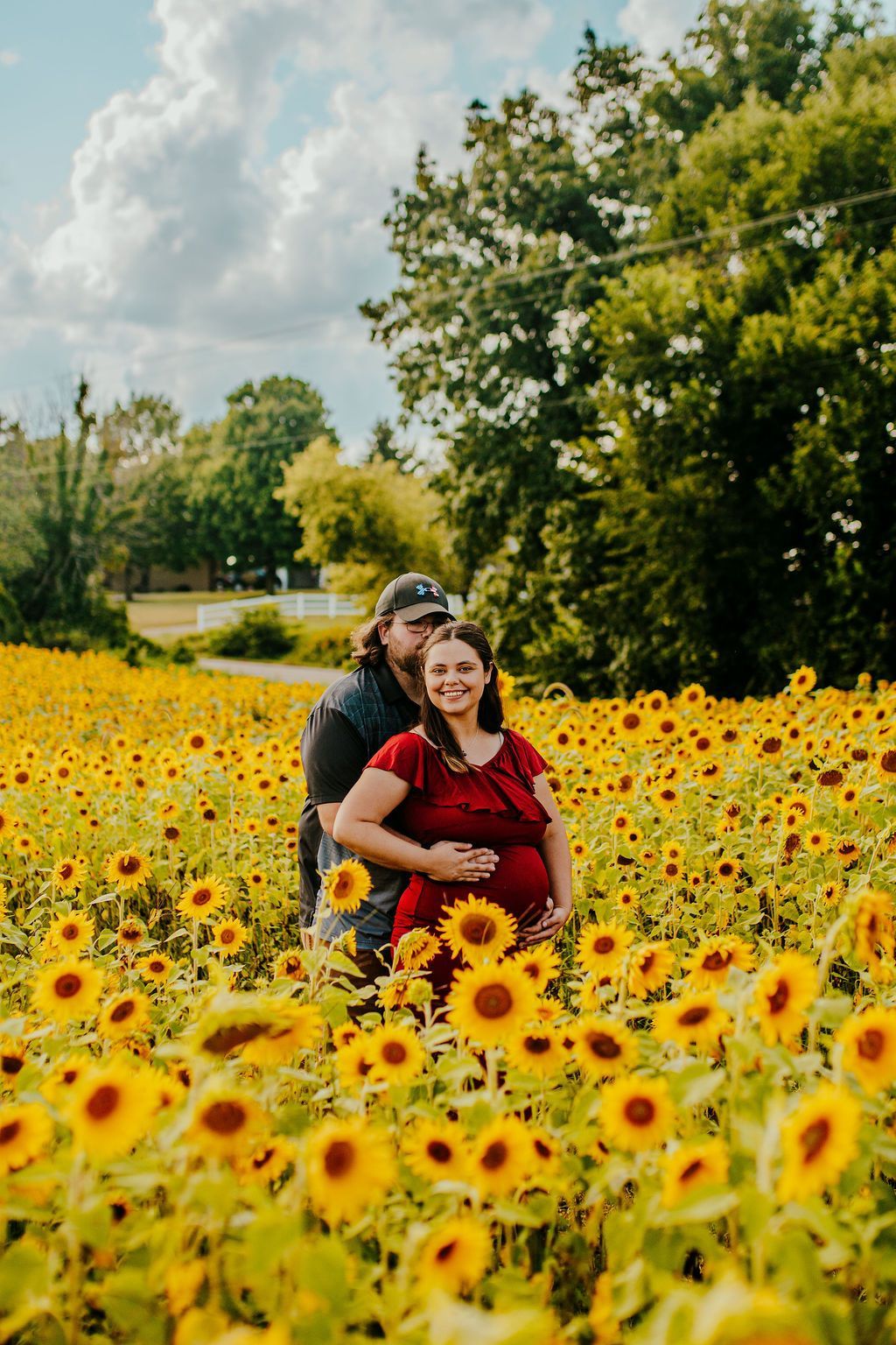 Couple embracing in a sunflower field under a cloudy sky