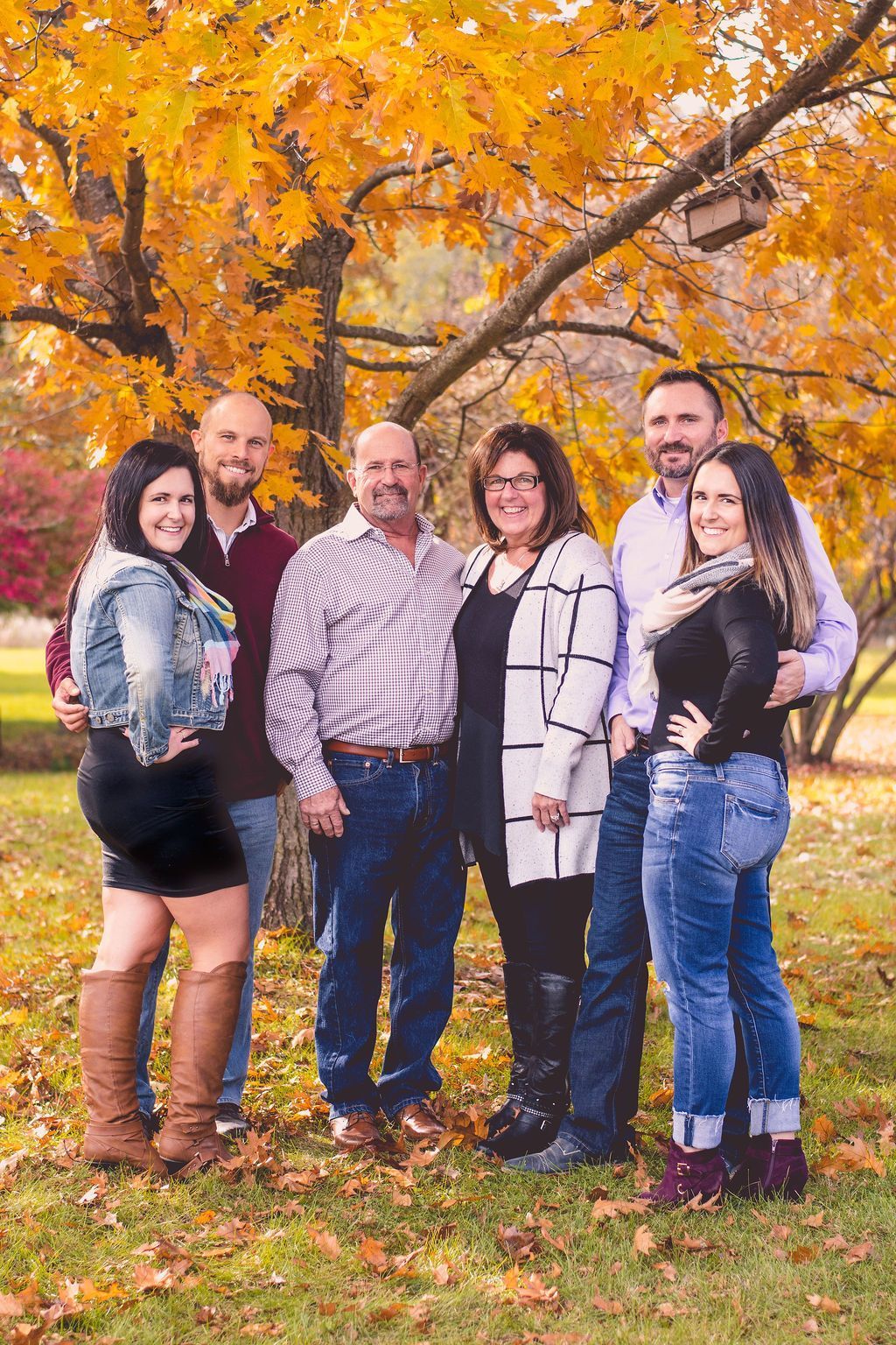 Five people standing together outdoors under orange autumn leaves, smiling at the camera.