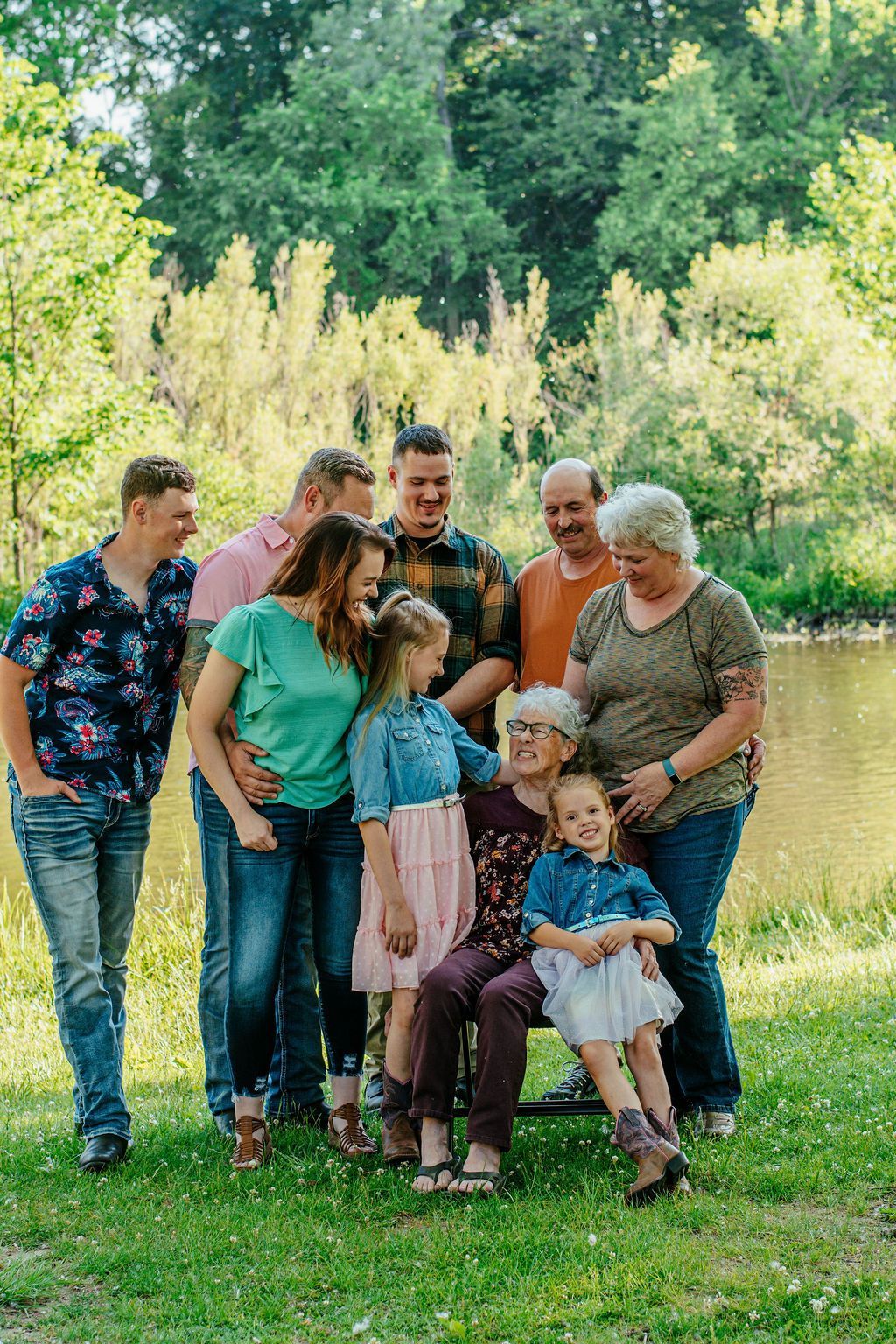 A group of people posing together outdoors in a grassy park, smiling and standing close.