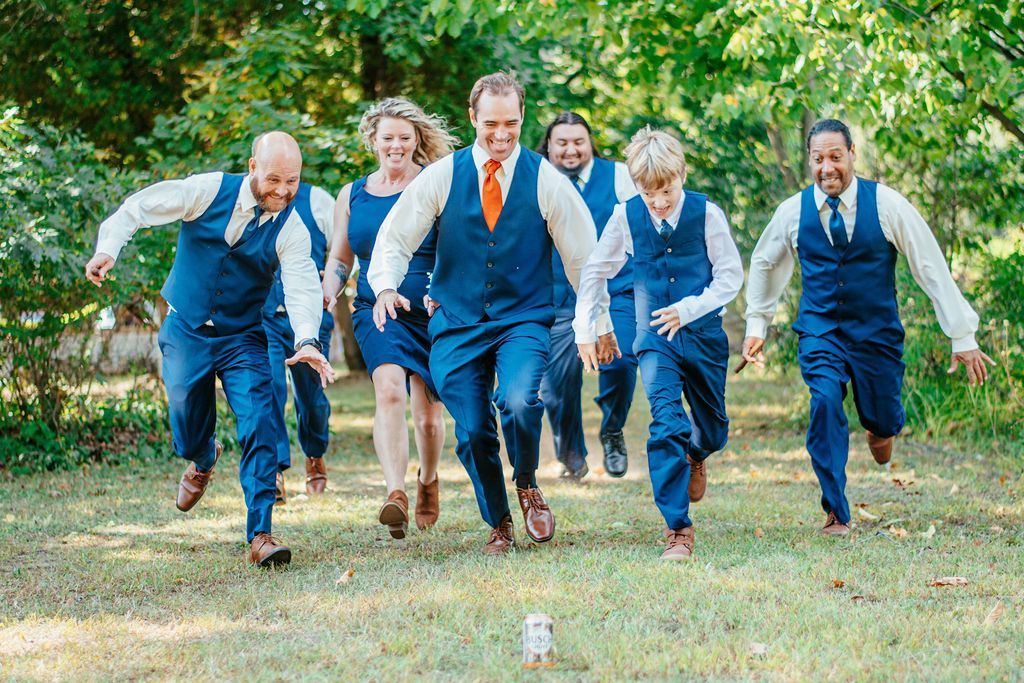 Group in blue vests running toward the camera on a grassy path under trees