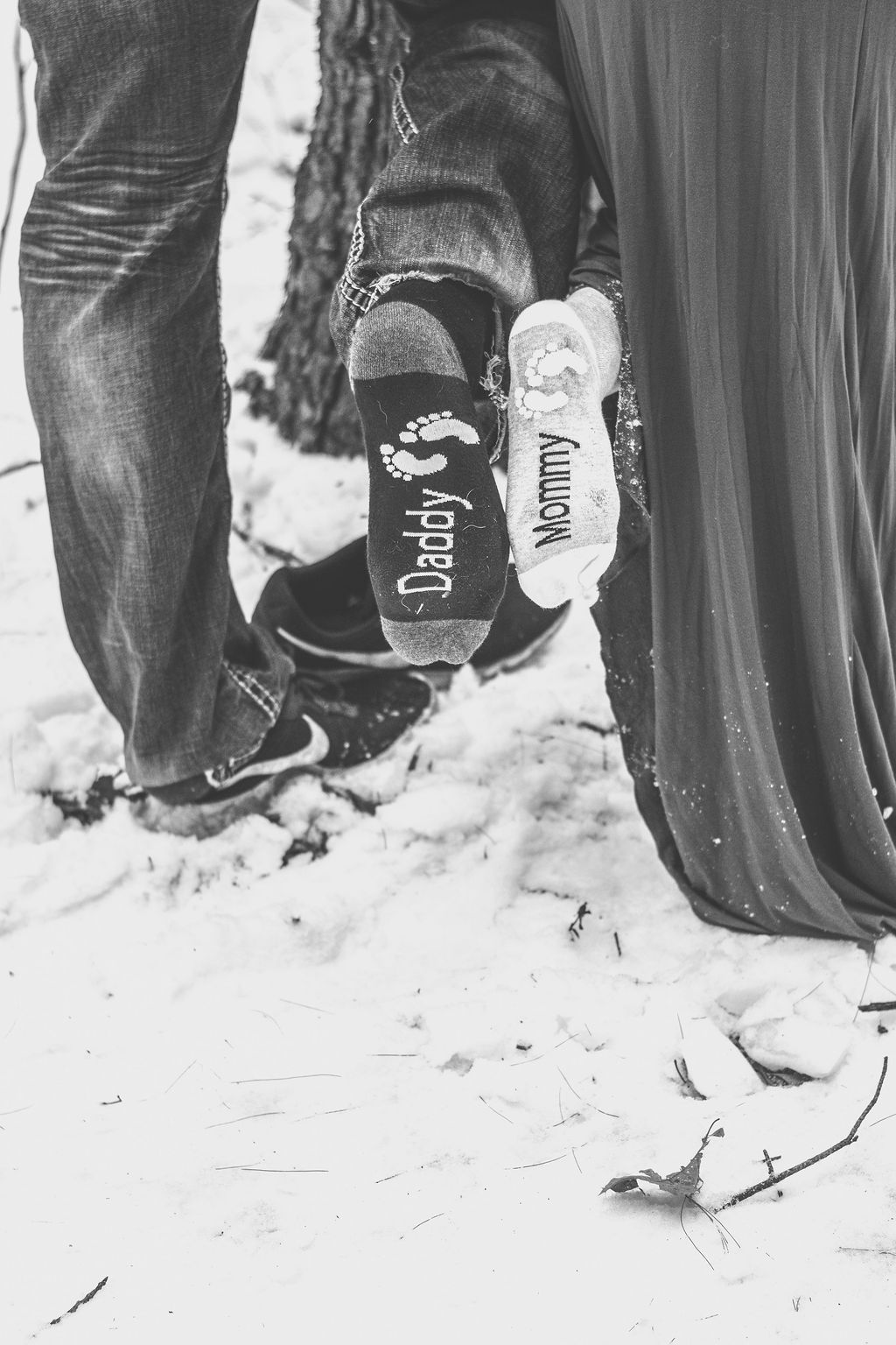Two people standing in snow, seen from behind, with a close-up of their shoes and legs