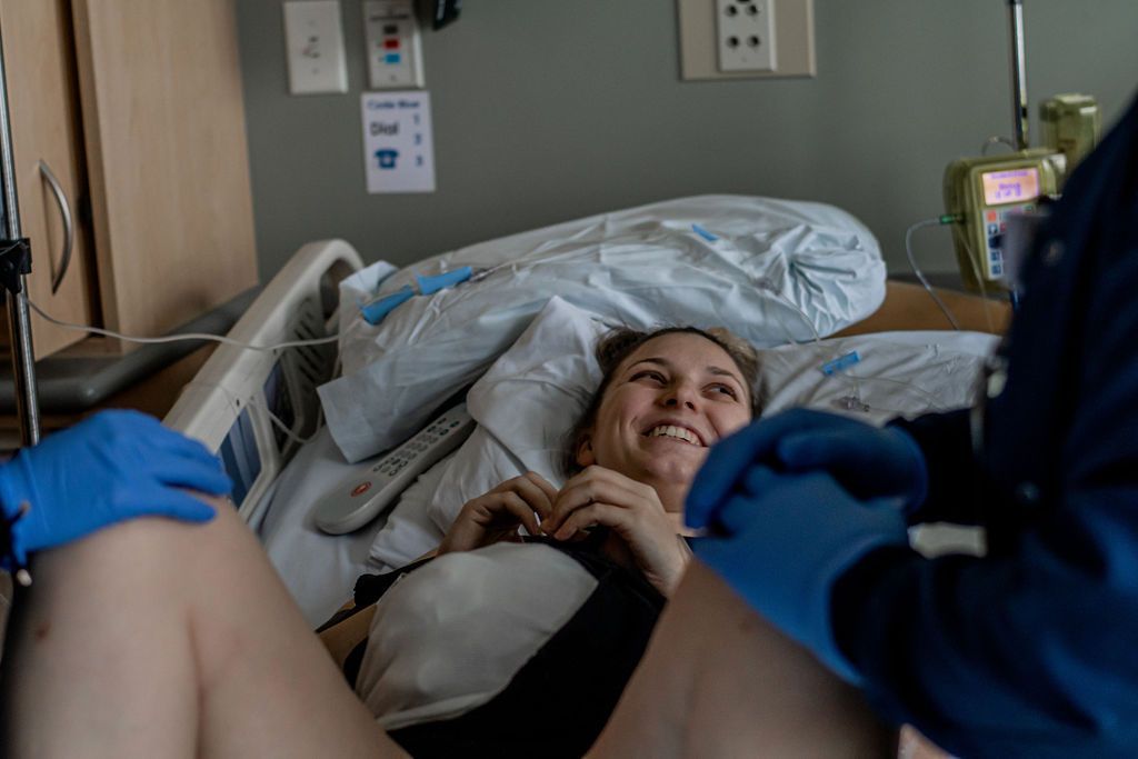 Patient lies in a hospital bed while gloved staff attend nearby