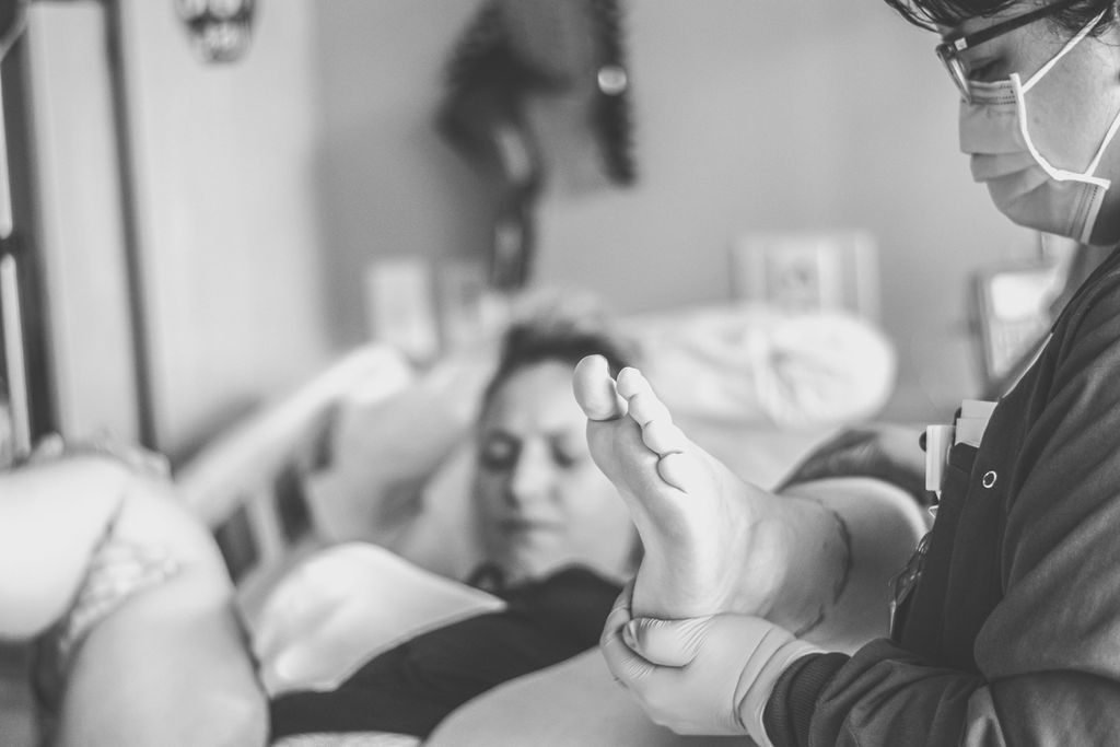 Healthcare worker examining a patient’s foot beside a hospital bed
