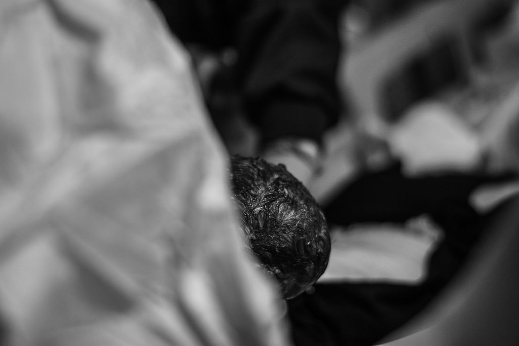 Blurred black-and-white scene of a person’s head in the foreground, with a crowd in the background