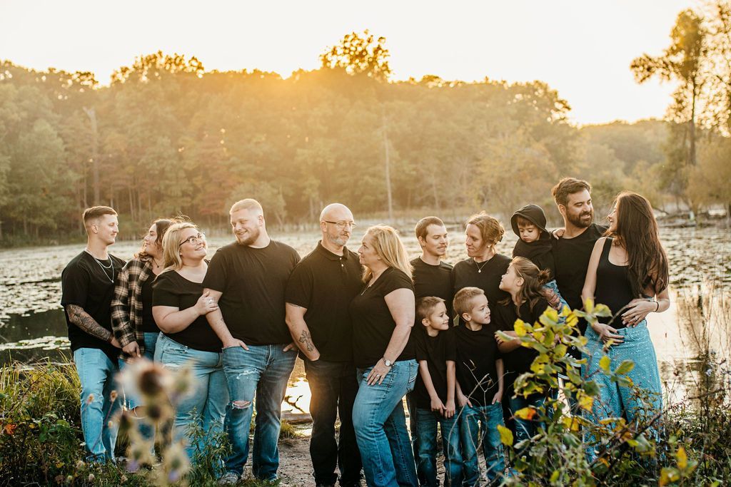 Group of people standing in a field at sunset, wearing black shirts and jeans.