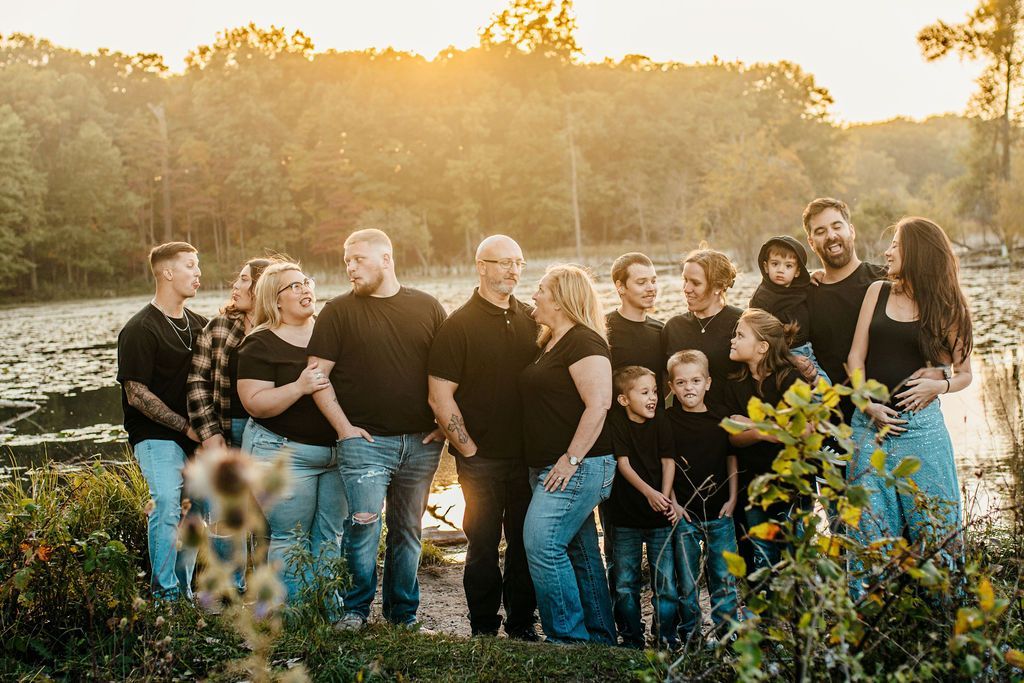 Group of people standing in a sunlit field at sunset, wearing black tops and jeans.