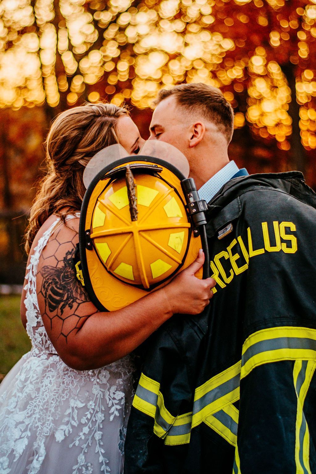 Bride and firefighter kissing with a yellow helmet in front of glowing lights