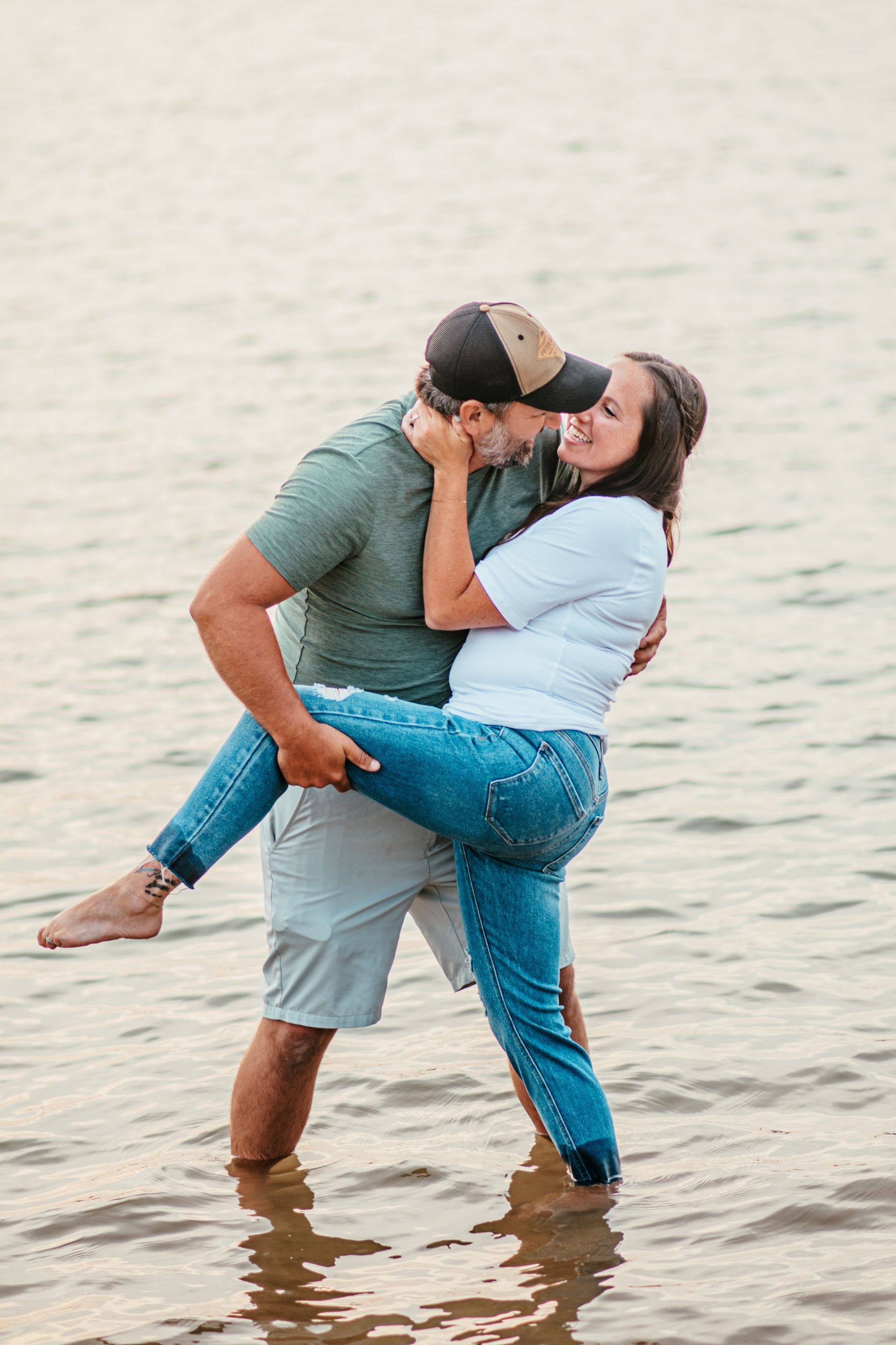 Couple kissing while the man carries the woman on a beach at sunset