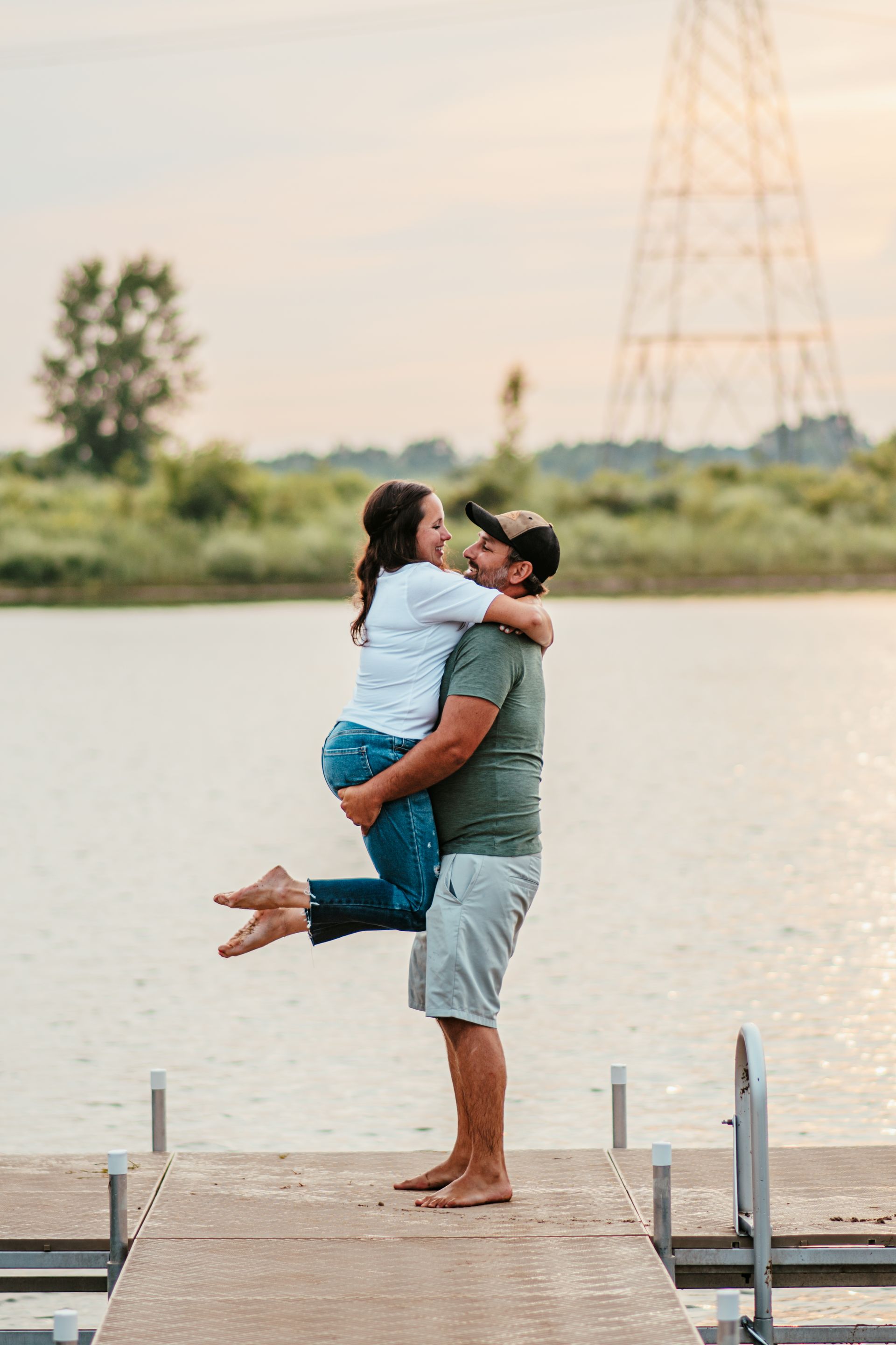 Couple embracing on a dock by a lake at sunset