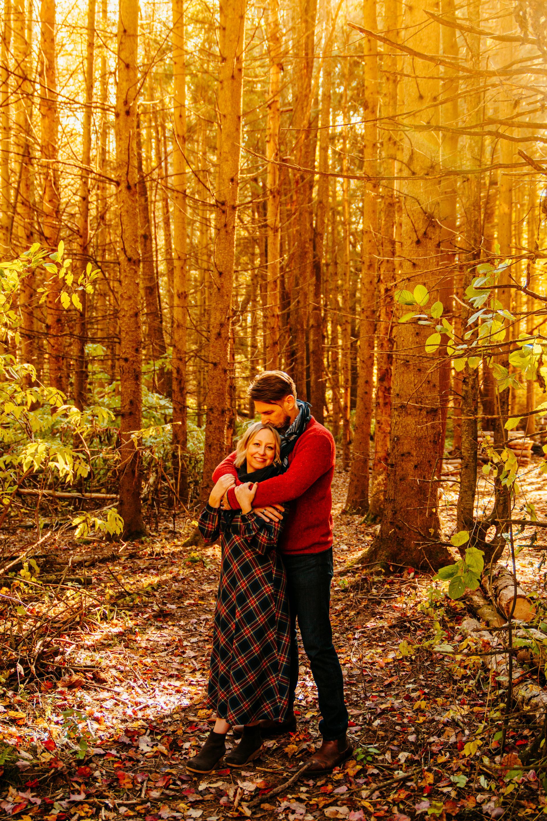 Couple embracing in a sunlit autumn forest with tall golden trees